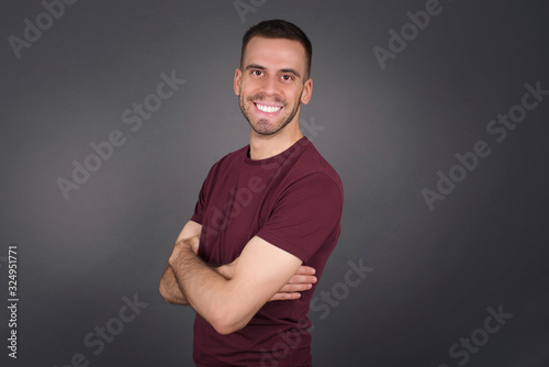 Image of cheerful pretty young caucasian businessman standing indoors with arms crossed. Looking and smiling at the camera. Confident boy.