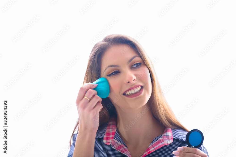 Naklejka premium Smiling beautiful woman applying blush to her face