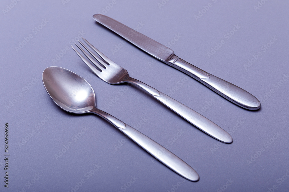 Silver fork, knife and spoon over grey background. Silver fork, knife and spoon over grey background.