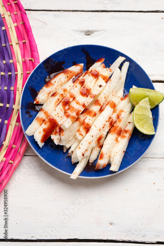 Mexican jicama  cutted with chili powder and piquant sauce on white background photo