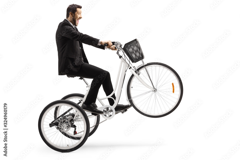 Man in a suit riding a white tricycle with front wheel up Man in a suit riding a white tricycle with front wheel up