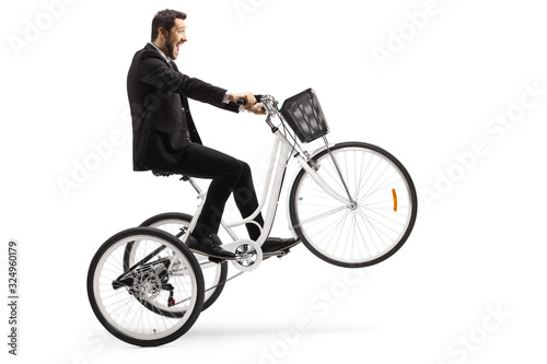 Man in a suit riding a white tricycle with front wheel up