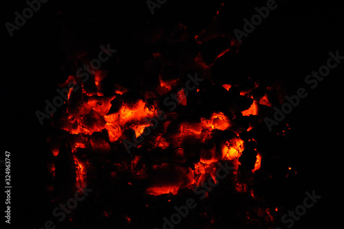 Background of burning hot coals. The flickering of burning coals in the night. Closeup