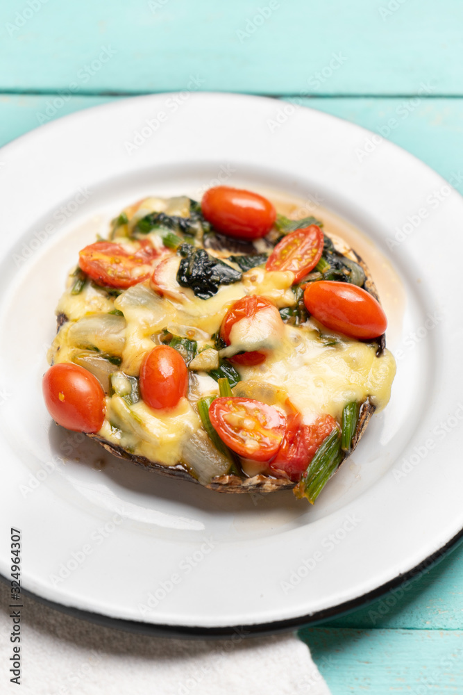 Portobello stuffed with spinach and cheese on turquoise background Portobello stuffed with spinach and cheese on turquoise background