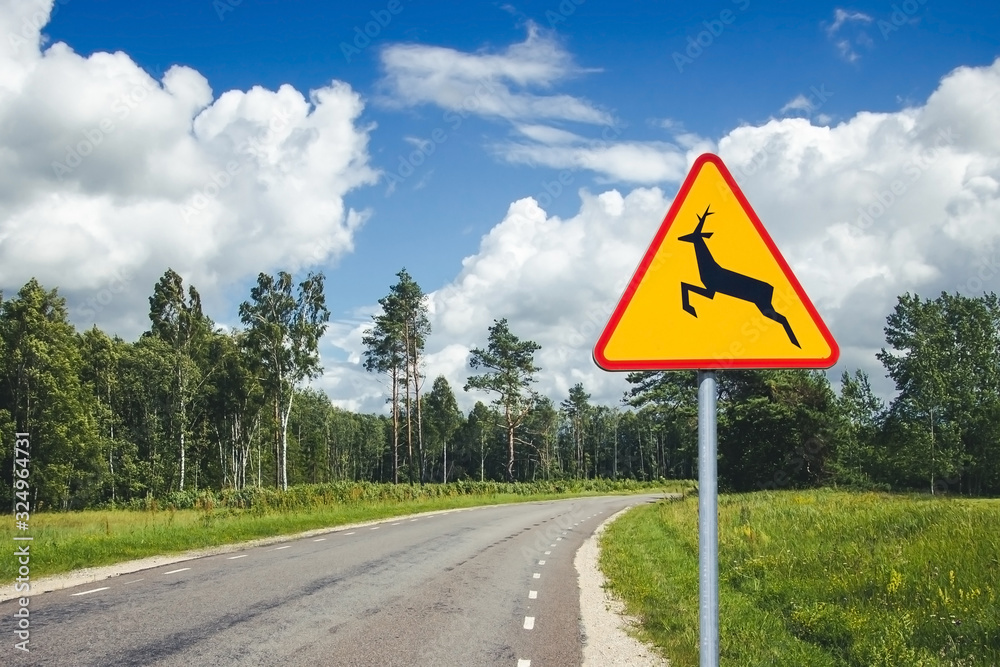 The Deer Crossing Warning sign. Dangerous accident may happen even on empty road. Be careful animals on the asphalt road.