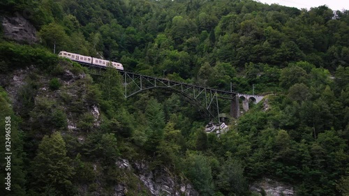 Scenic swiss train Centovalli Railway Locarno-Domodossola on bridge. Intragna village. Swiss Alps. Ticino Switzerland in summer, 4k.  photo