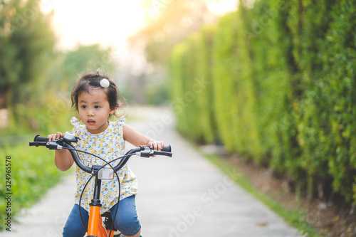 Lovely little asian girl riding a bike at bike lane outdoor.