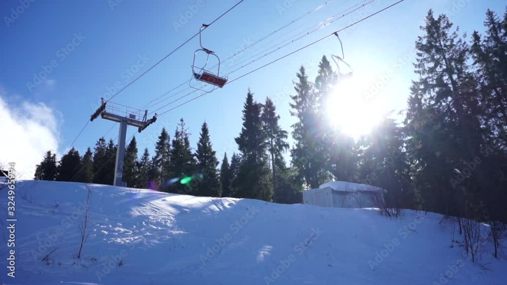 Cableway support with metal ropes moving the funicular chair equipment on a sunny blue sky background. Ski resort in the snowy mountain woods on a bright winter day. Cableway support with metal ropes moving the funicular chair equipment on a sunny blue sky background. Ski resort in the snowy mountain woods on a bright winter day.