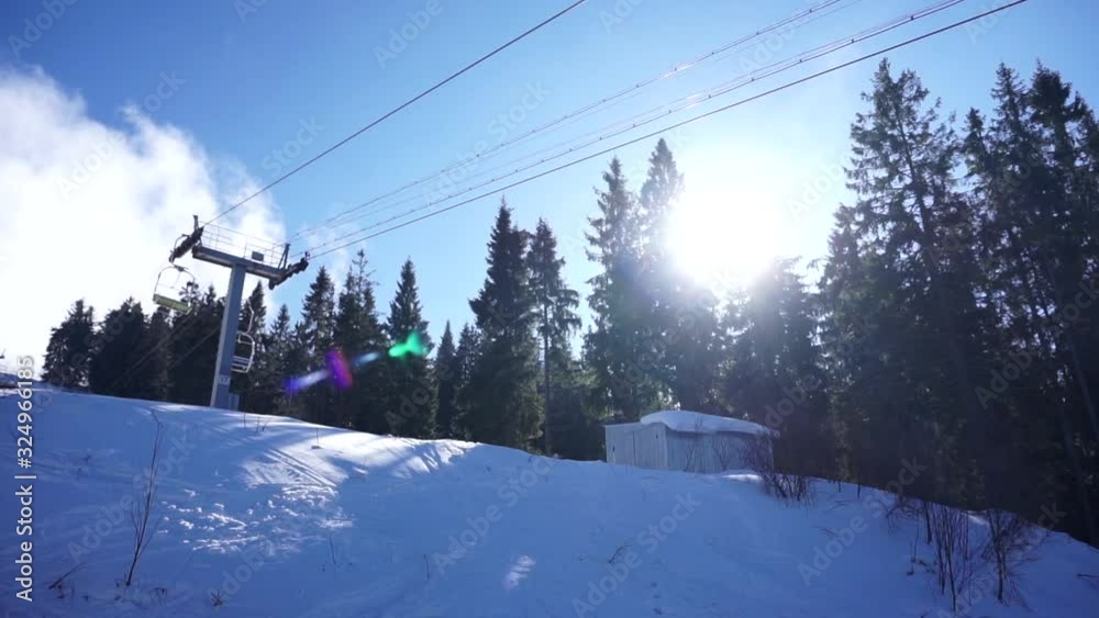 Cableway support with metal ropes moving the funicular chair equipment on a sunny blue sky background. Ski resort in the snowy mountain woods on a bright winter day. Cableway support with metal ropes moving the funicular chair equipment on a sunny blue sky background. Ski resort in the snowy mountain woods on a bright winter day.