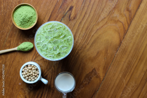 Top view,Closes up Iced Green Tea Matcha Latte on dark wooden tablle. Decorate with powder extract and soy beans, milk.