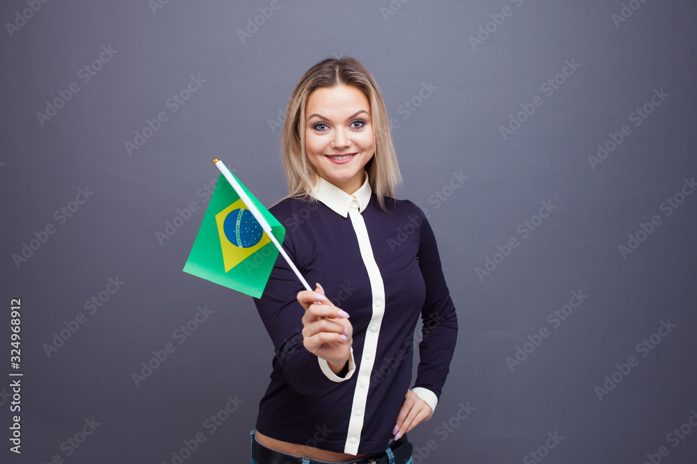 Immigration and the study of foreign languages, concept. A young smiling woman with a Brazil flag in her hand. Immigration and the study of foreign languages, concept. A young smiling woman with a Brazil flag in her hand.