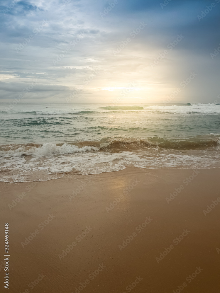 Beautiful image of sun rising over the calm ocean surface and sandy beach