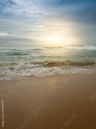 Beautiful image of sun rising over the calm ocean surface and sandy beach