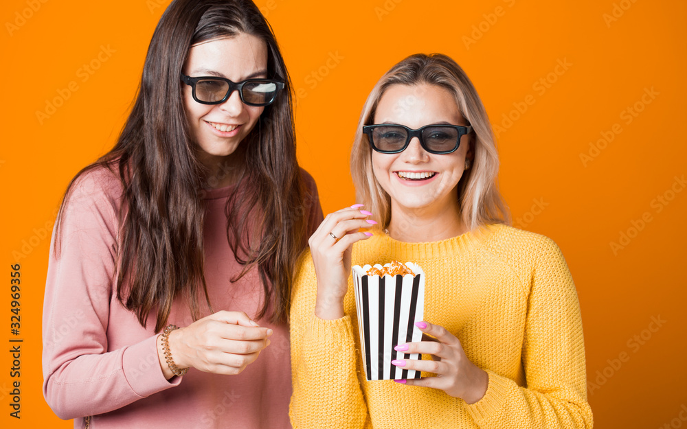 Two friends watch a movie or TV series and eat popcorn. Two young women fans of the movie,