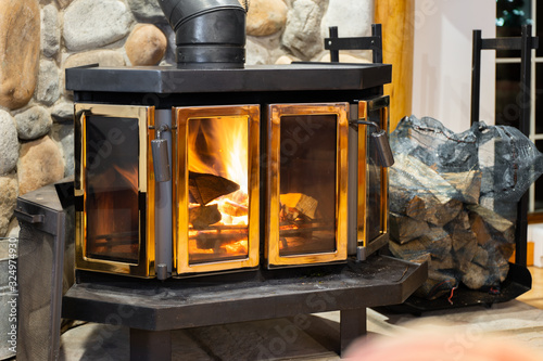 Wood stove fireplace with metal body and glass door in house with cozy interior photo