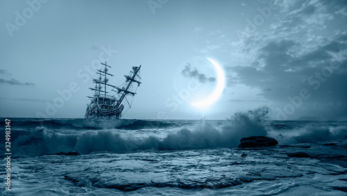 Sailing ship in storm sea against crescent moon