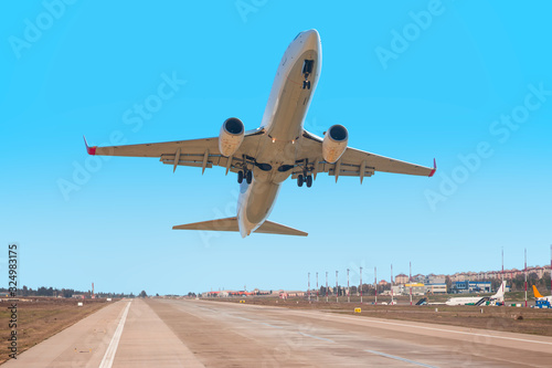 White Passenger plane fly up over take-off runway from airport 