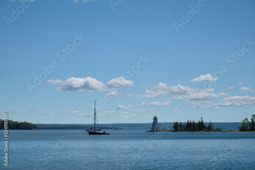 View on a bay with a sailboat and a lighthouse.