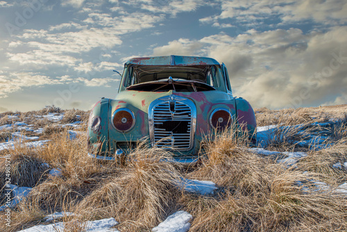 Fototapeta Naklejka Na Ścianę i Meble -  Abandoned car in the tall grass on a snowy hillside in Neidpath, SK