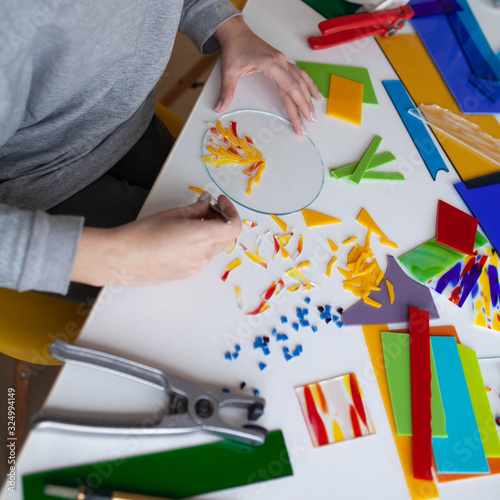 Woman puts out a mosaic of glass with tweezers, fusing, crafting photo