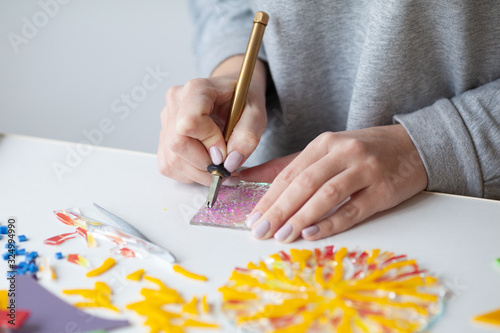 Woman puts out a mosaic of glass with tweezers, fusing, crafting photo