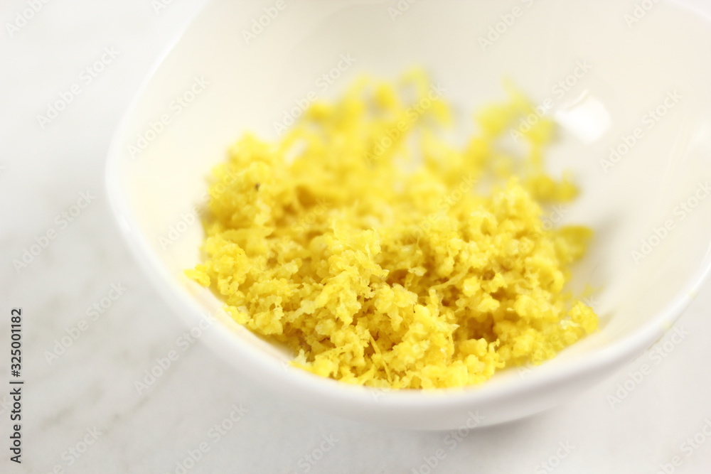 Shredded lemon rind in bowl. Making Lemon Mascarpone Pie Series. Shredded lemon rind in bowl. Making Lemon Mascarpone Pie Series.