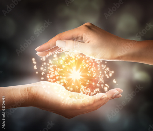 Female hands with shining energy on dark background