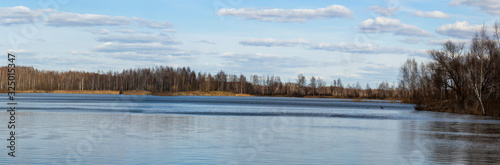 Landscape of early spring in nature. Lake with forest on shore against blue sky background with beautiful clouds. Banner format. Typical landscape of central Russia © ihorhvozdetskiy