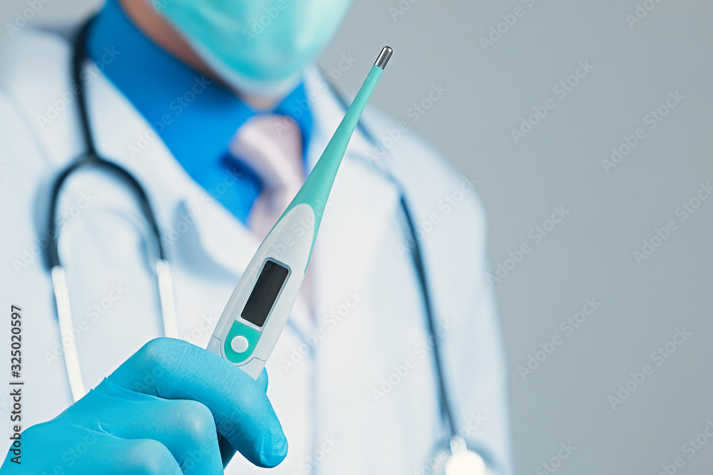 Doctor in gauze mask and medical robe holding thermometer in his blue rubber glove dressed hand Doctor in gauze mask and medical robe holding thermometer in his blue rubber glove dressed hand
