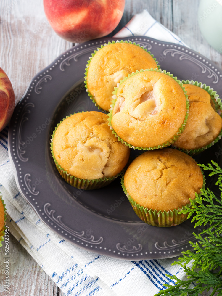 Vegan eggs free spelt wheat muffins with peaches and apples in green paper cases on checkered napkin Vegan eggs free spelt wheat muffins with peaches and apples in green paper cases on checkered napkin