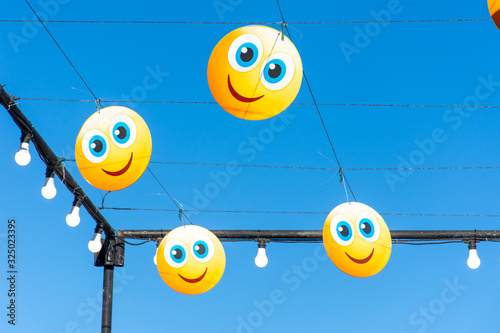 Hanging happy emojis or emoticons on blue sky for a street festival. Happiness, valentine's day, and joy concpets. photo