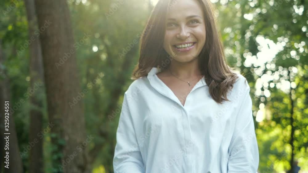A beautiful smiling woman with green eyes bounces and poses for a good keepsake photograph in a city autumn park among the trees. Photo session in a warm sunny park for a pretty girl in a white shirt. A beautiful smiling woman with green eyes bounces and poses for a good keepsake photograph in a city autumn park among the trees. Photo session in a warm sunny park for a pretty girl in a white shirt.