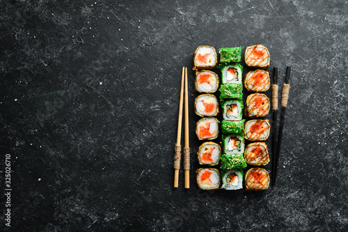 Big set of sushi rolls with seafood on a black stone background. Top view. Free space for your text.