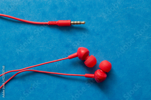 Red earphones on blue background, isolated earphones