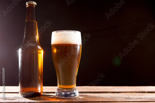 Cold tasty beer on a hot summer day. beer glass and bottle on dark table and wall background