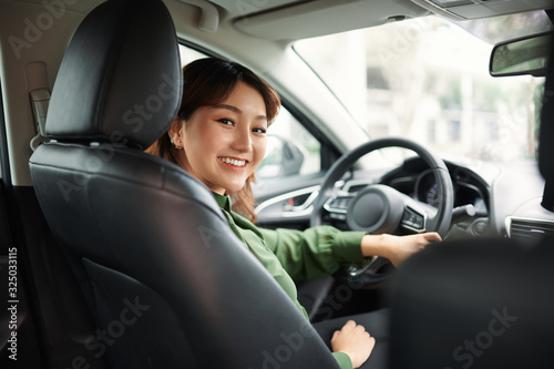 Smiling woman sitting in a car and looking back
