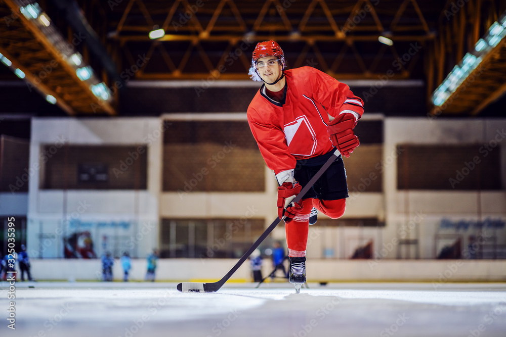 Fototapeta premium Full length of strong attractive hockey player skating towards goal and trying to make a score.