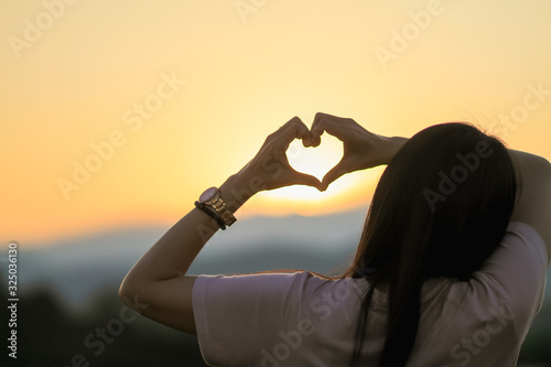 An Asian woman shows a heart symbol to tell her lover on Valentine's Day and the symbol showing love and friendship that has always been. photo