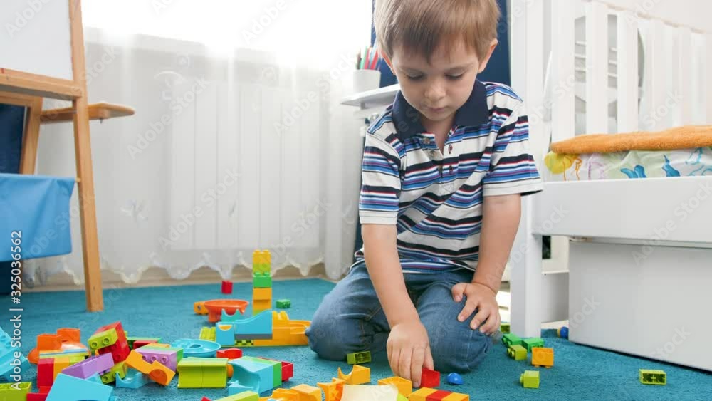 4k footage of little 4 years old boy building tower with colorful plasticks bricks and blocks