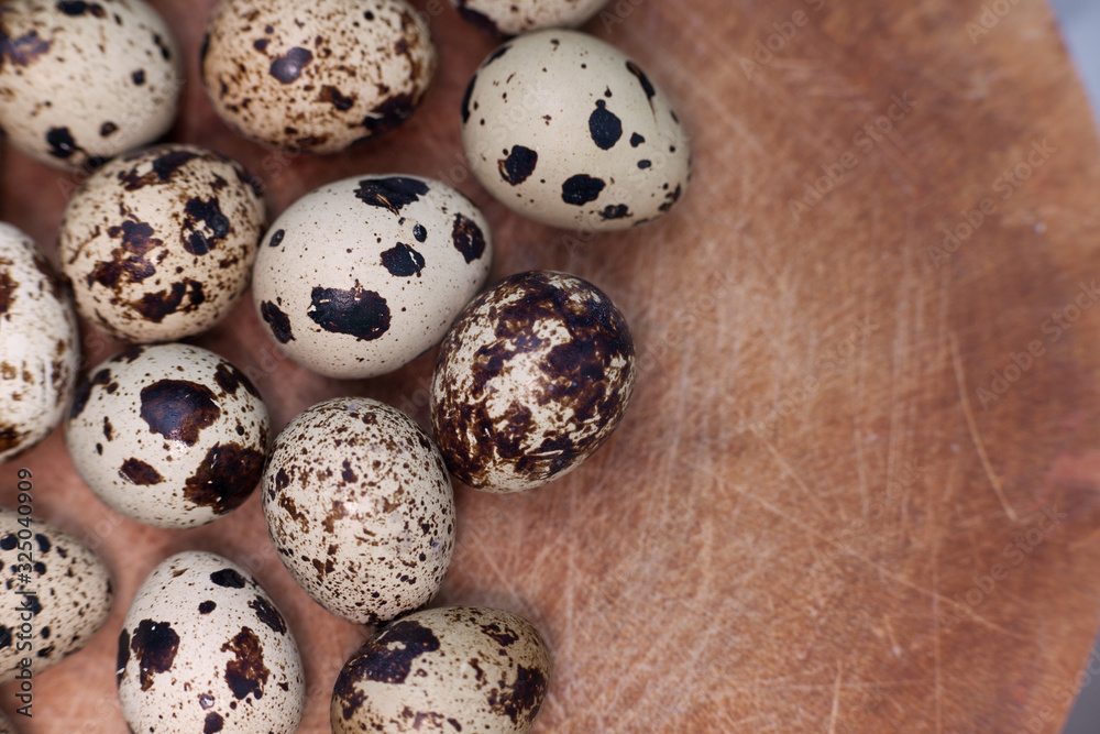 Quail eggs on a wooden board with a top view.