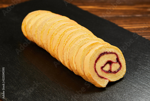 slice of festive sponge roll with jam on a wooden background