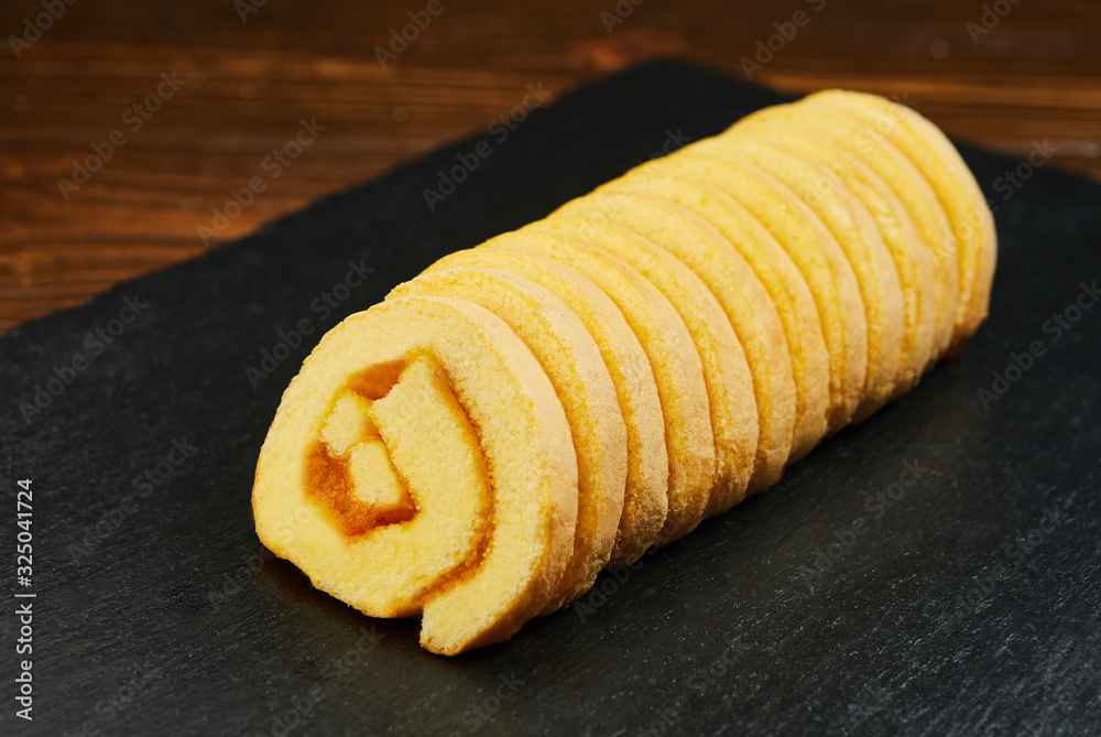 slice of festive sponge roll with jam on a wooden background slice of festive sponge roll with jam on a wooden background