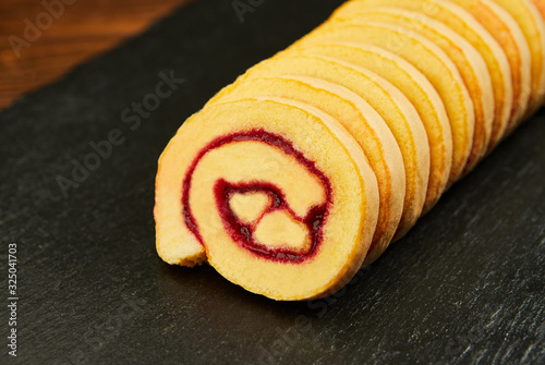 slice of festive sponge roll with jam on a wooden background