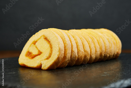 slice of festive sponge roll with jam on a wooden background