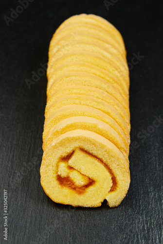 slice of festive sponge roll with jam on a wooden background