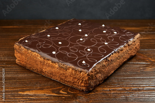 Dark chocolate vegan cake with candies and nuts on wooden background