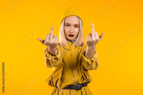 Принти на полотні Young rude woman on yellow background showing middle finger - gesture of fuck