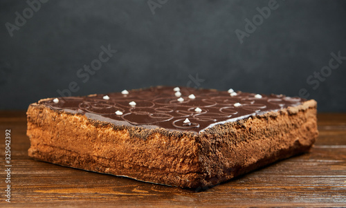 Dark chocolate vegan cake with candies and nuts on wooden background