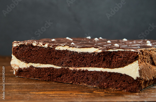 Dark chocolate vegan cake with candies and nuts on wooden background