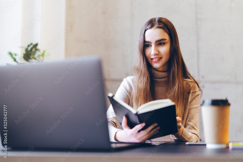 Woman studying for seminar, writing research paper, working on diploma project. Ambitious young specialist sitting at office desk, executing creative task, using laptop, Internet connection for job. Woman studying for seminar, writing research paper, working on diploma project. Ambitious young specialist sitting at office desk, executing creative task, using laptop, Internet connection for job.